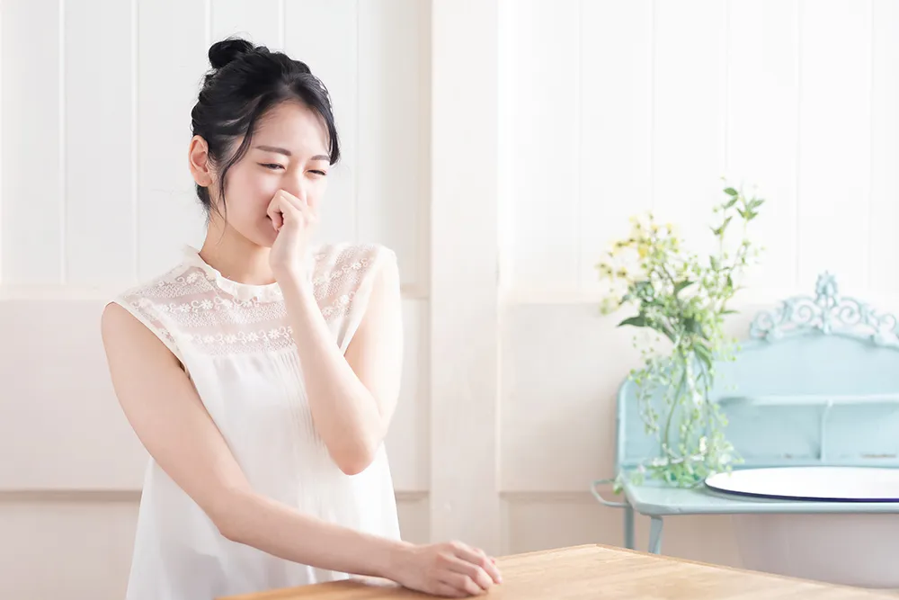 鼻をつまむ女性